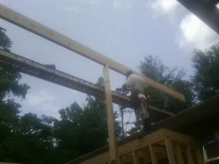 Carpenter setting a ridge beam over a new addition frame — Ice Dam Removal by Roofing Brothers in Locust Valley