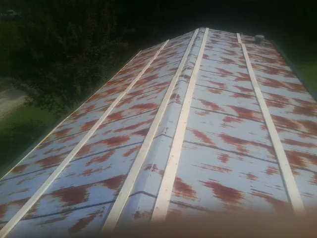 Rusted metal roof panels with new wood purlins before replacement — Storm Damage Roof Repair in Locust Valley by Roofing Brothers