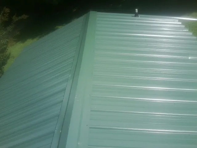 New green metal panels meeting at the ridge of a roof — Flat Roof Repair work by our crew in Locust Valley