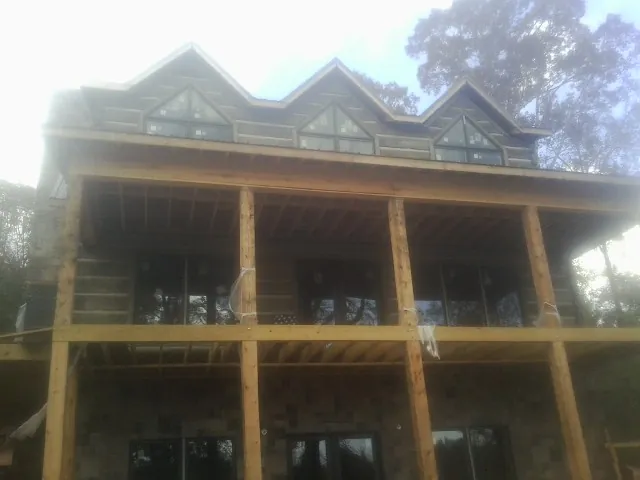 Dormers and porch framing on a large log home under construction — Roof Coating work by our crew in Locust Valley