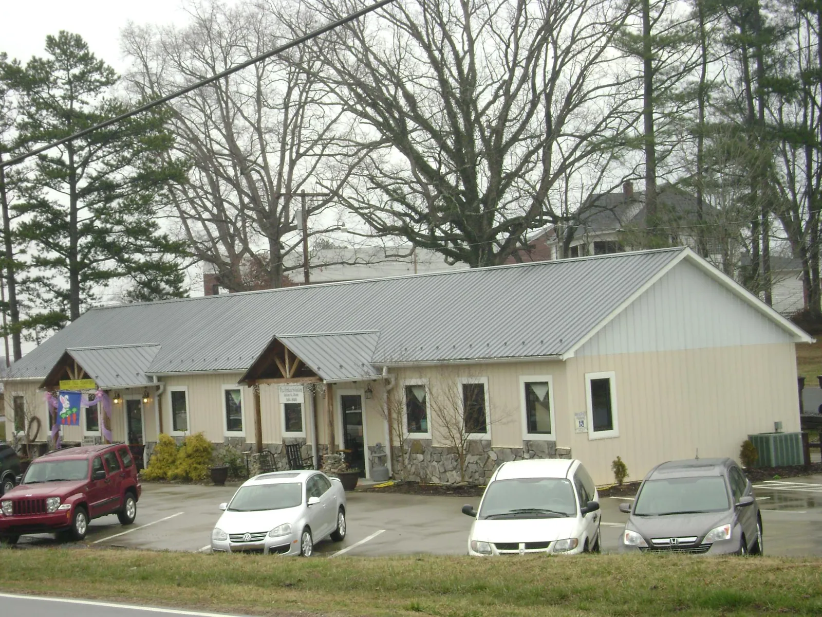 Gray metal roof with timber entry brackets on a small commercial building in Locust Valley