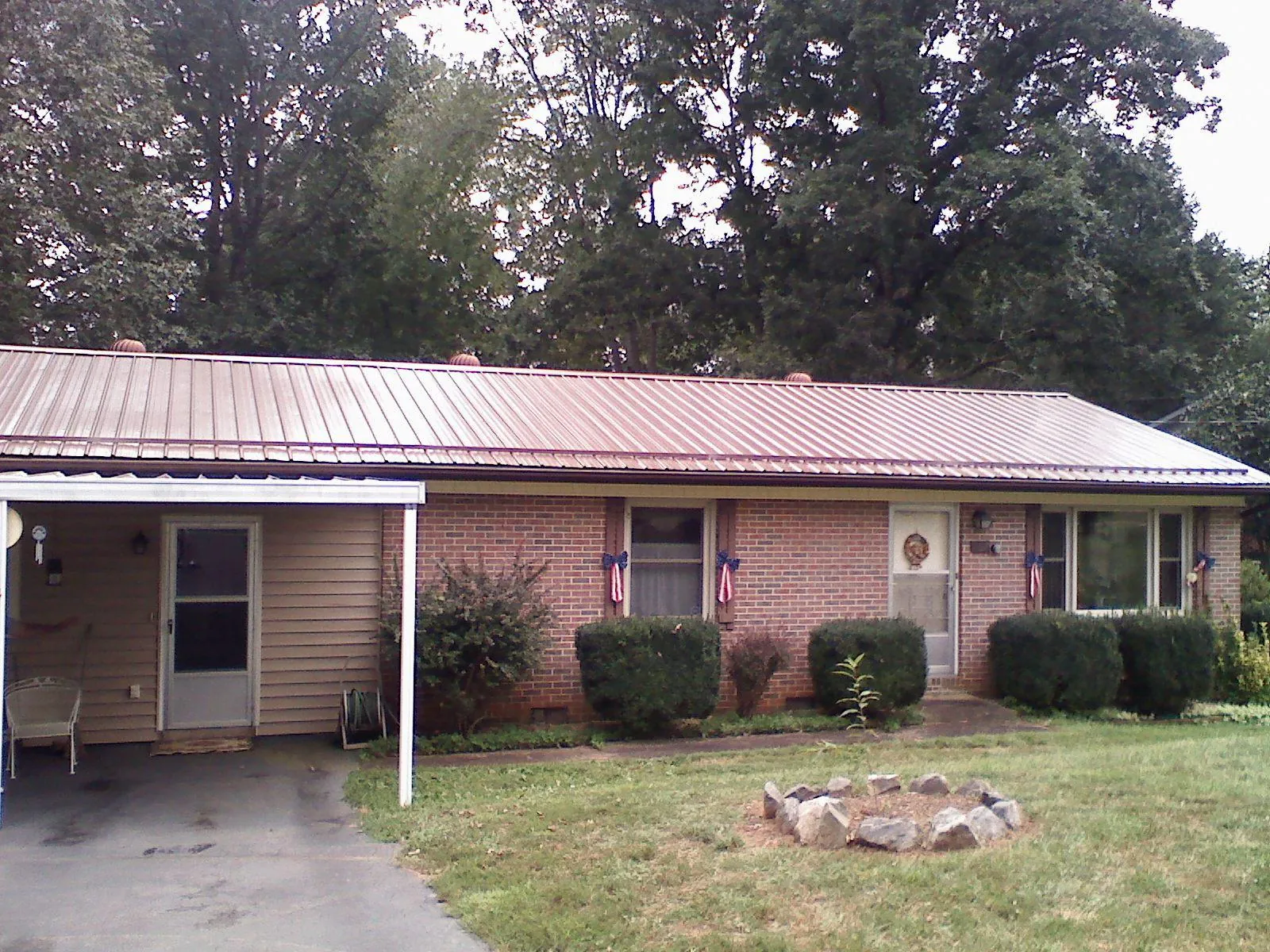 Bronze metal roof and carport on a brick ranch home — Roof Repair work by our crew in Locust Valley